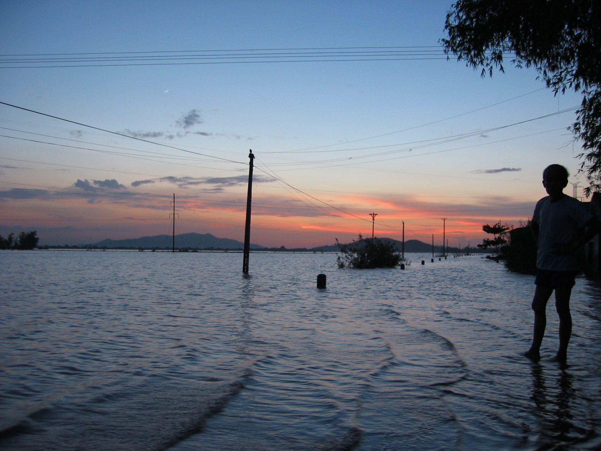 Tropical sunset over inundated area with a silhouette of a person.