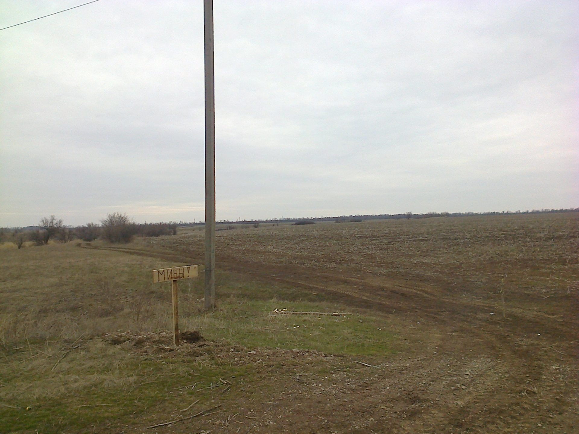 Open field with sign indicating presence of mines.